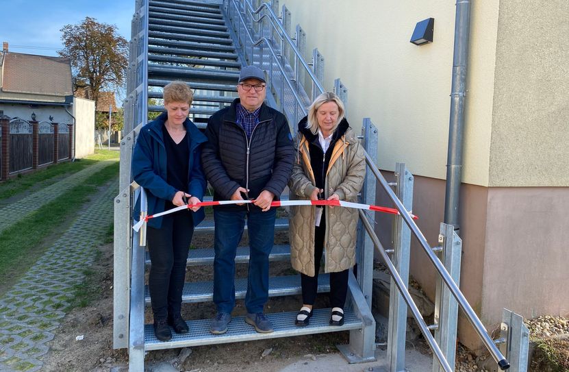 Die LEADER-Regionalmanagerin Katrin Lohmann, Ortsvorsteher Steffen Jahrow und Bürgermeisterin Simone Taubenek beim Banddurchschnitt auf der neugebauten Außentreppe.