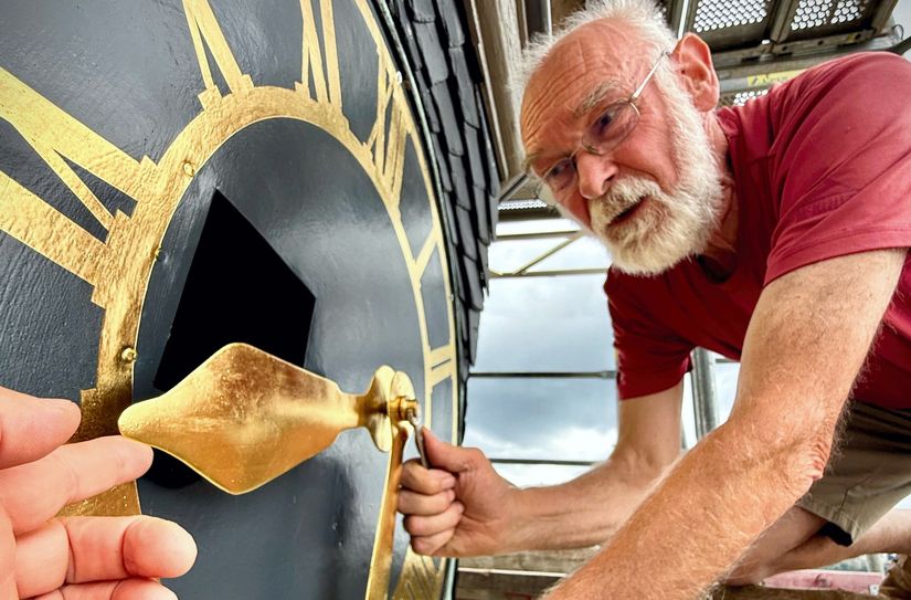 Feinmechaniker Markus König, der die Restaurierung der Uhr initiiert hatte, bringt die Zeiger an.