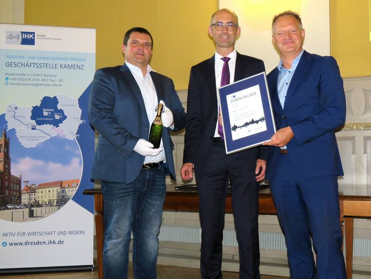 Im Beisein von Oberbürgermeister Frank Höhme (l.) nimmt der Geschäftsführer der Radeberger Exportbierbrauerei Olaf Plaumann (r.) die IHK-Ehrenurkunde von IHK-Hauptgeschäftsführer Lukas Rohleder (m.) entgegen. OB Höhme hat eine historische Bierflasche aus dem Jahr 1887 in seinen Händen.
 Foto: Matthias Stark