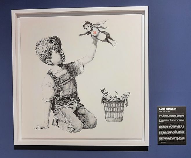 "Game Changer" zeigt einen kleinen Jungen, der Batman und Spiderman im Spielzeugkorn liegelnlässt und mit seiner neuen Superheldin spielt: Einer Krankenschwester-Puppe mit Maske. Banksy brachte das Bild unerkannt in ein Krankenhaus in Southampton, das Werk durfte versteigert werden und der Erlös in Höhe von 19,4 Millionen Euro steht dem britischen Gesundheitswesen zur Verfügung.