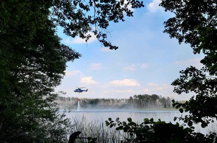 Zwei Hubschrauber helfen bei der Brandbekämpfung und schöpfen Wasser aus einem See.
