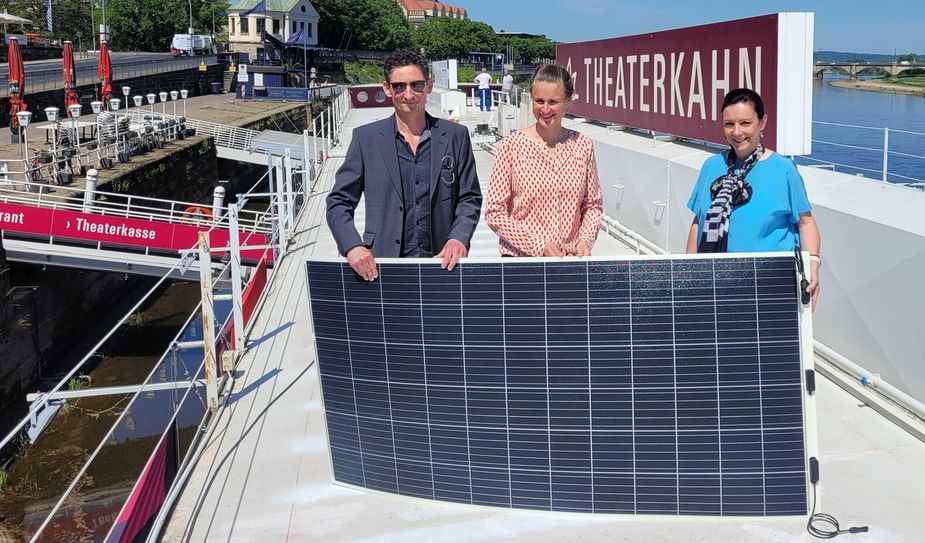 Übergabe eines Solar-Panels durch die SachsenEnergie-Projektverantwortliche Ines Kirner (re.) an Theaterkahn-Intendant Holger Böhme (li.)