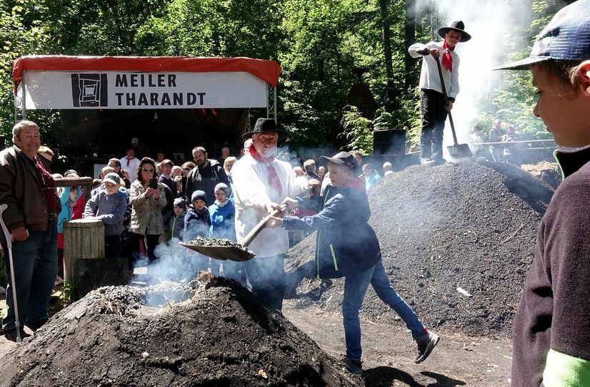 Felix (10) bestückt »seinen« Kinder-Meiler gemeinsam mit seinem Opa Bernd Papperitz (73) mit Glut, füllt sie mit der Schaufel in den Feuerschacht.