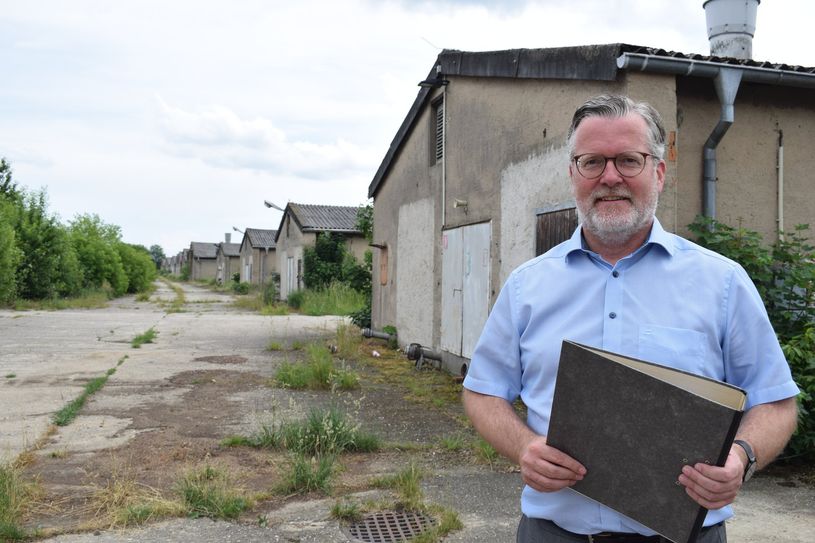 Bürgermeister Swen Nowotny steht auf dem ehemaligen Schweinemast-Gelände an der B96. Ein Investor möchte die Gebäude abreißen lassen und im benachbarten Feld bauen.