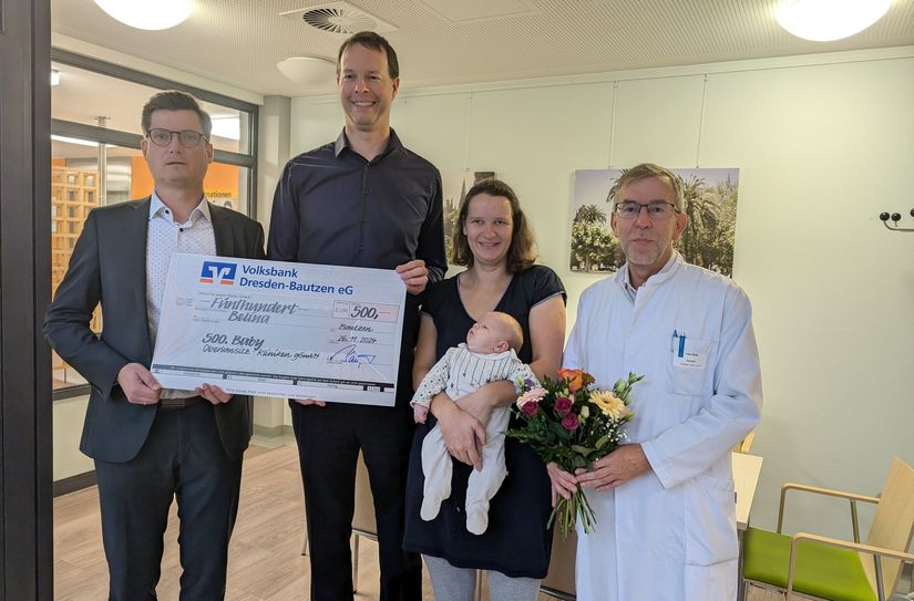 Andreas Baumgärtel von der Volksbank (l.) und der Ärztliche Direktor Frank Weder (r.) beglückwünschen Baby Belina sowie ihre Eltern Manuel und Theresa Kuzaj.