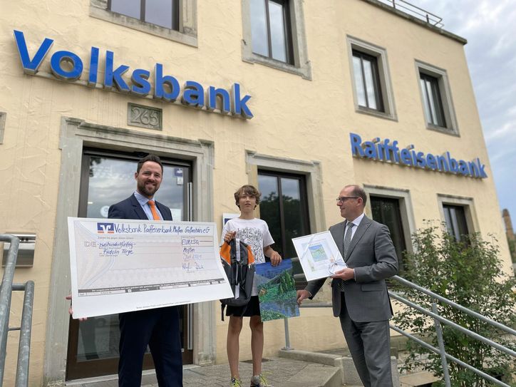Preisträger Fridolin Torge (Mitte) nimmt in der Geschäftsstelle Radebeul seinen Gewinn von Pressesprecher Marcus Müller (links) und Vorstandsmitglied Claus-Michael Zwiebel (rechts) entgegen. Foto: PR