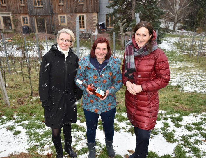 Schirmherrin Annett Hofmann (r.) und Initiatorin Daniela Kreissig (l.) mit der nominierten Winzerin Anja Fritz. Sie hält eine Flasche der Edition »Frieden« in den Händen. Blick von ihrem Weinberg auf das Weinbergshaus im Hintergrund. Foto: Trache