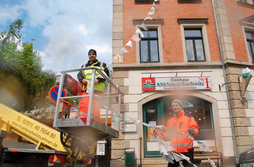 Veranstaltungstechniker Clemens Wießner (li.) und sein Assistent Wieland Dörr lassen sich vom schlechten Wetter nicht beeindrucken und schmücken die Dorfmeile mit bunten Wimpeln.