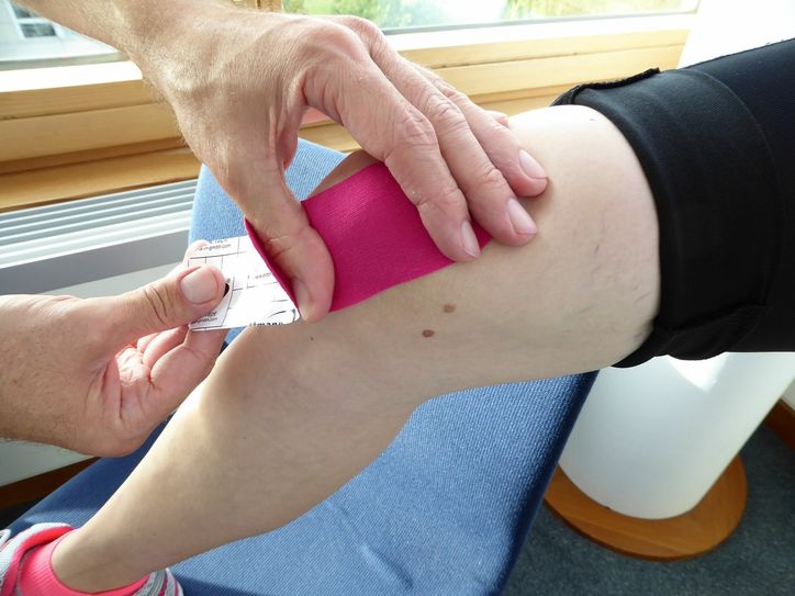 Ein Knie wird mit einem Tape belegt.