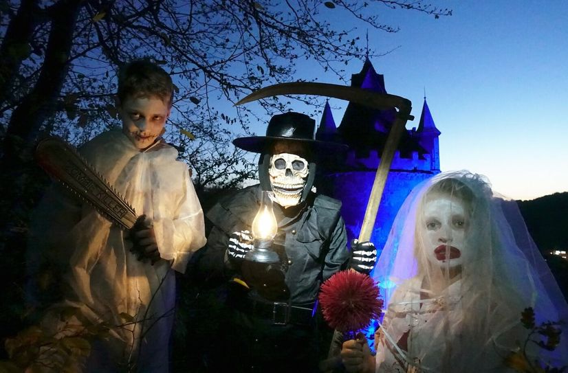 Nick (11) hat sich als Zombie-Killer verkleidet, Anika (12) geht als weiße Frau. Gemeinsam posieren sie mit dem Sensenmann vor dem mystisch angeleuchteten Schloss Kuckuckstein.