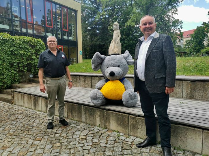 Gerhard Lemm (links/Oberbürgermeister der Stadt Radeberg) und Uwe Lammeck (rechts/Geschäftsführer Heinrichsthaler Milchwerke GmbH) bei der symbolischen Übergabe einer Plüsch-Käsemaus im Innenhof des Radeberger Rathauses. Foto: (PR/Heinrichsthaler)