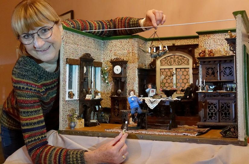 Christel Göpel mit einer Puppenstube, ein dunkel gehaltenes Herrenzimmer.