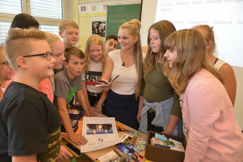 Melanie Reinecke (Mitte) ist jetzt als Lehrerin an der Grundschule am See in Senftenberg tätig. Im Foto zeigt sie den Schülerinnen und Schüler der Klasse 6a im Englischunterricht ihre Souvenirs von ihren Reisen rund um die Welt. Foto: Peter Aswendt