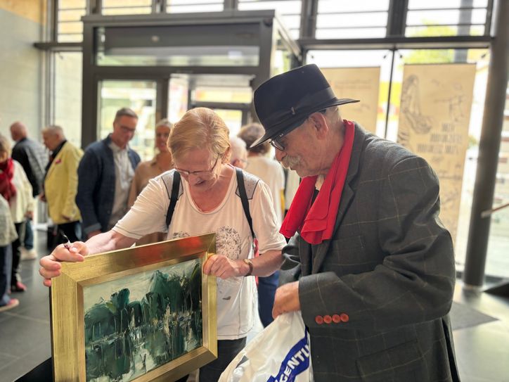 Maler Günther Rechn signiert in der Rathausgalerie ein Bild aus seinem Atelier, das seit über 20 Jahren der Senftenbergerin Barbara Schönherr gehört.