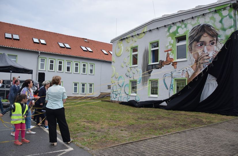 Kinder und Erwachsene enthüllen das Wandbild am Wasserwerk.