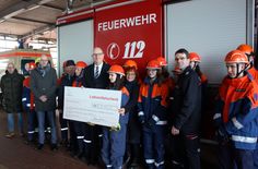 Ministerpräsident Dietmar Woidke überreicht den symbolischen Scheck an Robert Buder, Vorstandsvorsitzender des Kreisfeuerwehrverbandes, und die Jugendlichen, die am Wahlpflichtfach teilnehmen.