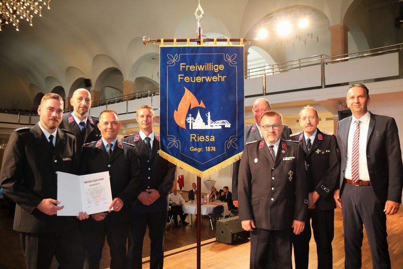 Stadtwehrleiter Robert Gudat und die Stadtteilwehrleiter vor der neuen Fahne - rechts OB Marco Müller, hinten ((halb verdeckt) Frank Ricklin vom Kreisfeuerwehrverband.