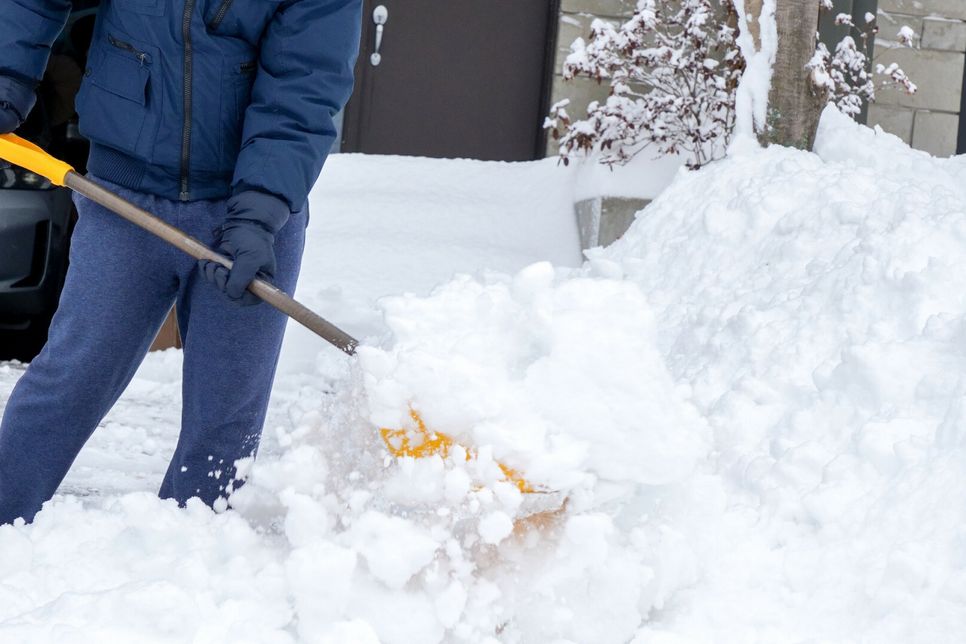 Ein Mann schiebt Schnee auf seiner Auffahrt. Das kann durchaus gefährlich werden.