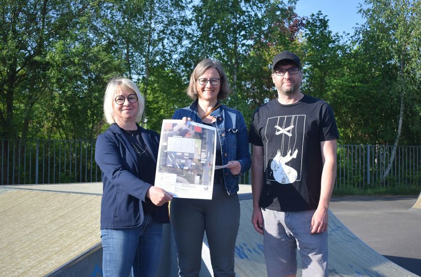 Andrea Zickler, Bauamtsmitarbeiterin, Anne Steiniger, Planungsbüro Subatzus und Bringmann, und Steve Kroß, Sozialarbeiter, mit einem Plan der neuen Skater- und Basketballanlage.