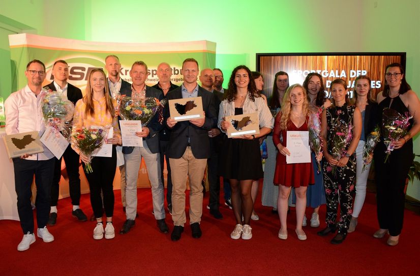 Gruppenfoto mit den ausgezeichneten Sportlerinnen, Sportlern und Mannschaften im Kreis.