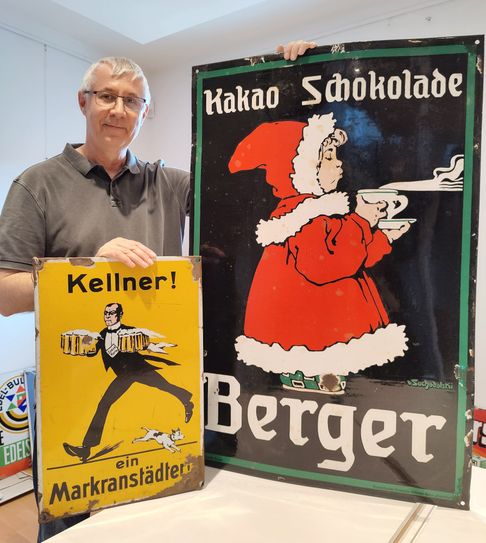 Olaf Weber, wissenschaftlicher Mitarbeiter des Museums, präsentiert zwei der gezeigten Emailschilder.
 Foto: Museumsverbund Elbe-Elster