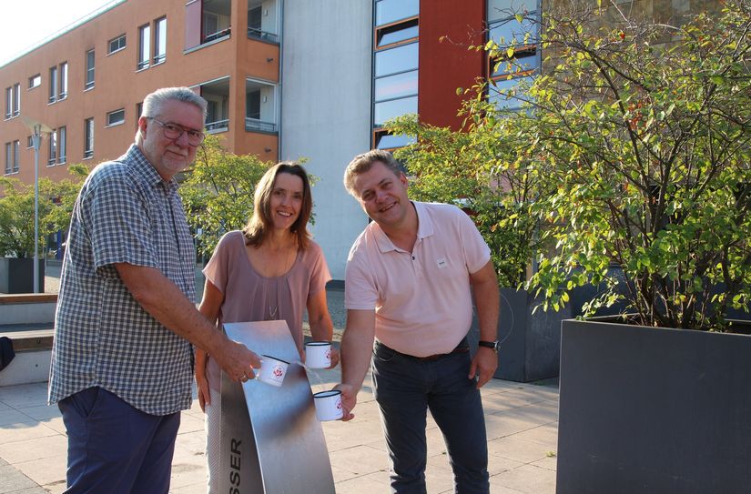 Oberbürgermeister Thomas Schubert, Bürgermeisterin Friederike Trommer sowie Jörg Morgenstern von der WAB Coswig mbH testen den neuen Trinkwasserbrunnen.