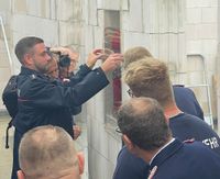 Der Grundstein - als historischer Feuerlöscher - wird in der Wand des Gebäudes als Zeitkapsel für den Neubau eingemauert.