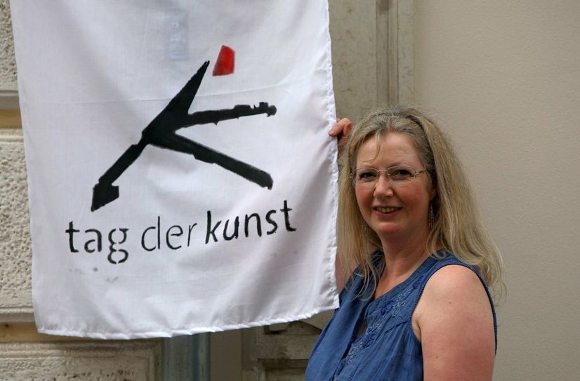 Organisationschefin Brigitta Arnold mit dem Logo des Kunsttages. Die weißen Fahnen ziehen sich durch die gesamte Altstadt.