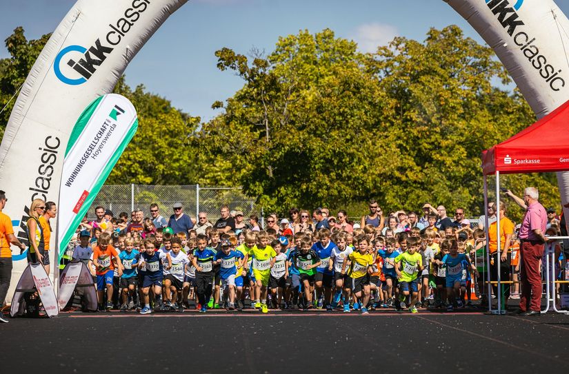 Oberbürgermeister Torsten Ruban-Zeh (r.) gibt den Startschuss für den VBH-Grundschullauf. Die Mädchen und Jungen sprinten los.