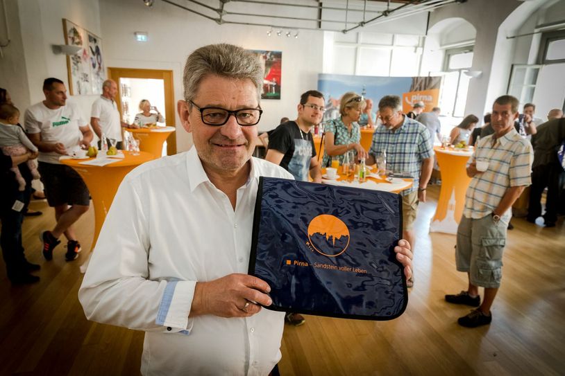 Diese Pirna-Tasche, die der OB zeigt, mit  allen wichtigen Informationen und Unterlagen erhielten alle Zuzügler. Und natürlich fehlten auf den Tischen auch Birnen, die zum Stadtwappen gehören, nicht.