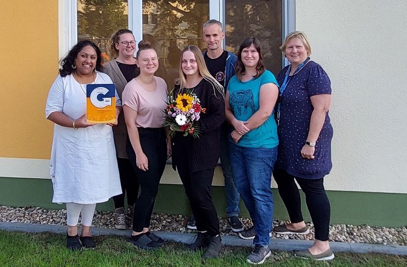 Madhura Mariyappa von pädquis überreicht das Siegel an Franziska Scholta, Paula Höppner, Lisa Gorgs, Dirk Bernheiden, Melanie Jainz und Andrea Neitsch von der Wadelsdorfer Kita.