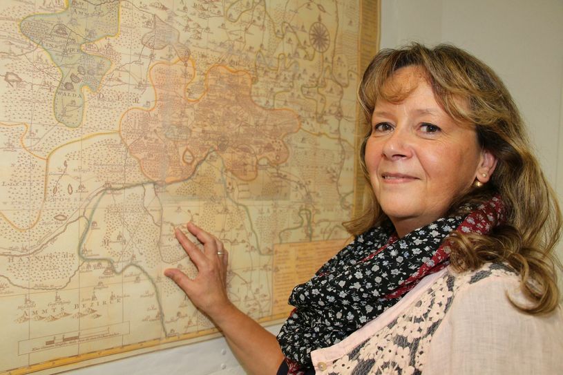 Stadtarchivarin Ines Jahn steht vor einem von vielen Prachtstücken im Stadtarchiv Senftenberg: Es ist eine reproduzierte Ansicht des „Ammtes Senftenberg“ aus dem Jahr 1757. Eine Vielzahl von Informationen lassen sich aus der Kartes ablesen. Foto: sts
