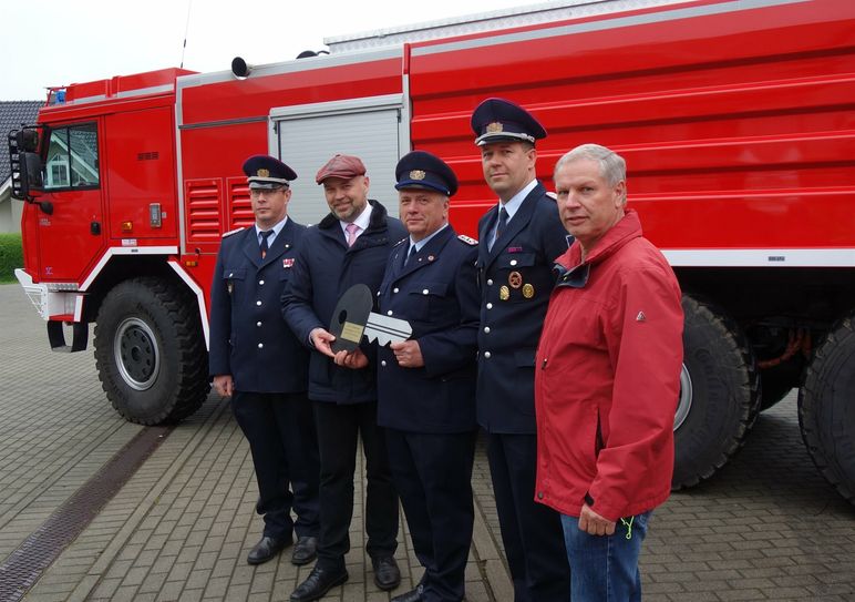 Im Beisein von Amtswehrführer Marcus Weber (l.) und dem Vorsitzenden des Amtsausschusses, Joachim Dieke (r.) übergibt Amtsdirektor Tobias Hentschel (2.v.l.) den symbolischen Fahrzeugschlüssel für das hinter ihnen stehende GTLF an Gerätewart Jens Buder (m.) und Ortswehrführer Daniel Scheiter.