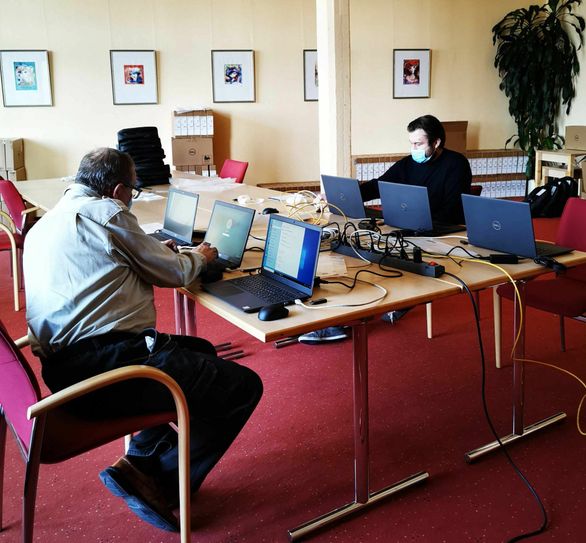 Mitarbeiter der Stadtverwaltung Guben brachten die neuen Laptops in Betriebsbereitschaft. Im Hintergrund sind die 80 Laptops für die Friedensschule-Grundschule, welche auf die Freigabe der Schulleitung warten, zu sehen. Foto: Stadt Guben/ Böhme