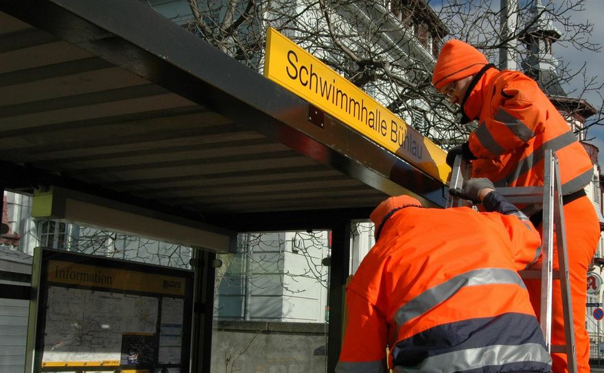 Mitarbeiter der Verkehrsbetriebe bringen die neue Beschilderung an den Wartehäusern der Haltestelle an. Foto: Pohl