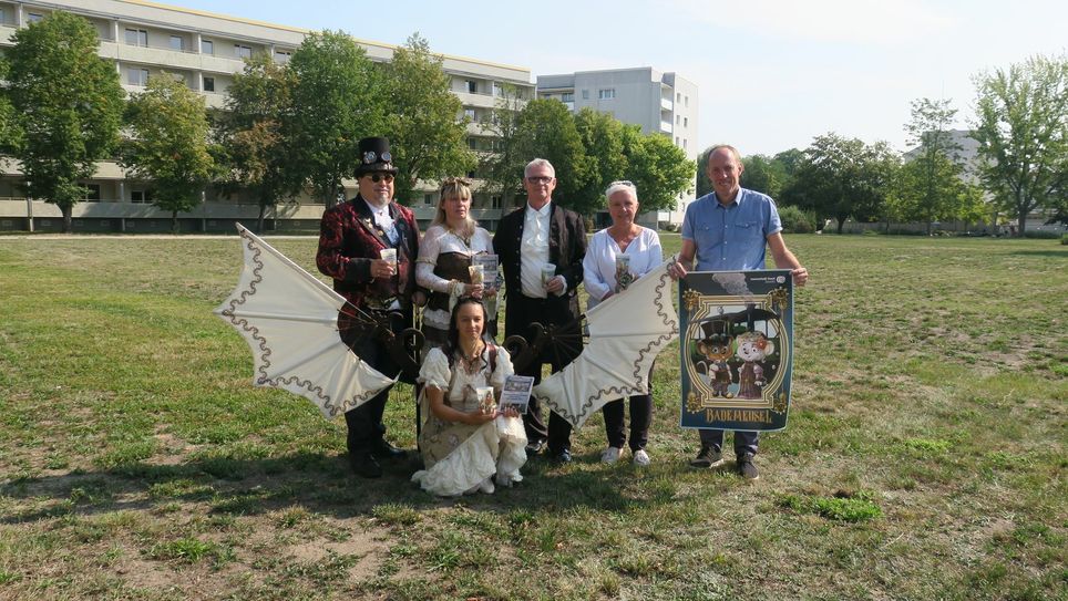 Auf der großen Festwiese hinter dem Platanenhain an der Stadtkirche, präsentieren Bürgermeisterin Simone Taubenek (2.v.r.), Stefan Palm (r.) sowie eine kleine Gruppe des Steamrose-Teams die kleinen und ab sofort erhältlichen Gadgets. Am Veranstaltungstag werden sich auf diesem Platz zudem die Bühne, die Händler und die Versorgungsstände befinden. Foto: Dany Dawid