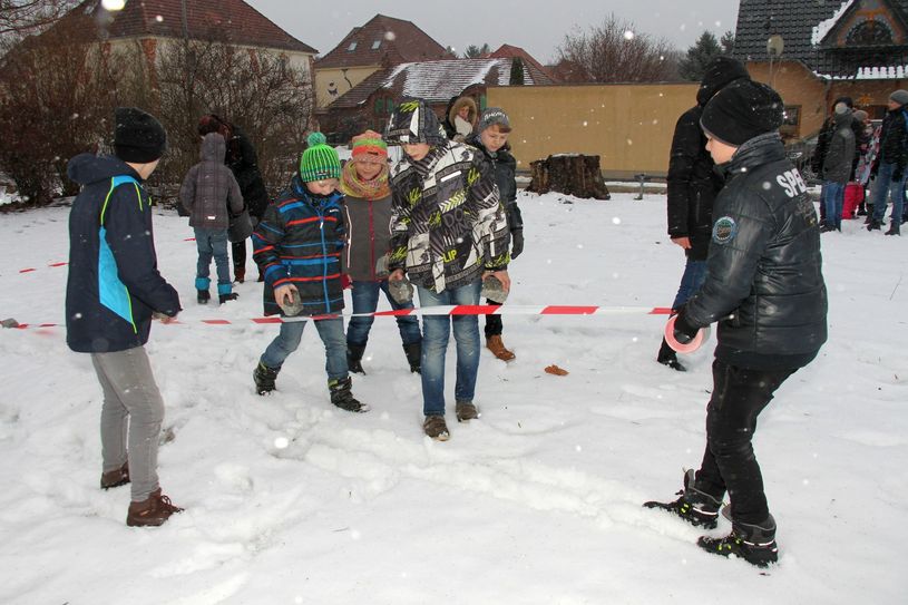 Mit rot-weißem Absperrband und grauen Pflastersteinen markieren Kinder aus dem Ortsteil Brieske die Fläche auf dem vorhandenen Spielplatz, auf der demnächst neue Spielmöglichkeiten nach ihren Wünschen entstehen sollen. Ihr Ergebnis: 11,80 Meter mal 16,50 Meter. Der Schneeschauer störrt sie dabei nicht. Foto: sts