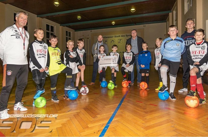 Maik Domel, 1. Vorsitzender des Vereins (rechts), und Roland Münzer, der Trainer der Mannschaft (links), freuten sich über die Scheckübergabe von Thomas Schatter (hinten links im Bild).