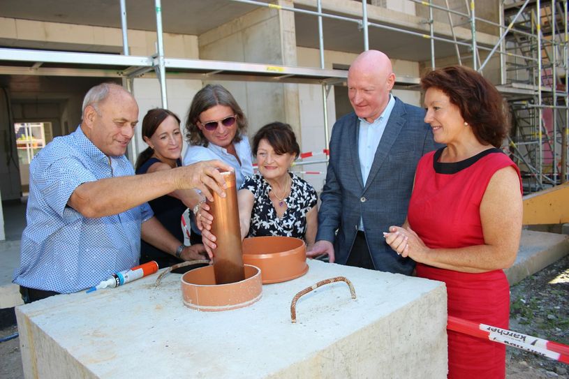 Verschlossen und eingemauert: Die Kartusche ist endlich dort angekommen, wo sie schon seit Monaten hätte liegen sollen. Ein Feiertag für die Bauherrenfamilie Diethart, Jana, Jan und Brigitte Packroff. Auch zur Freude von ILB-Vertreter Bernhard Eichner und Anja Heinrich. Foto: wit