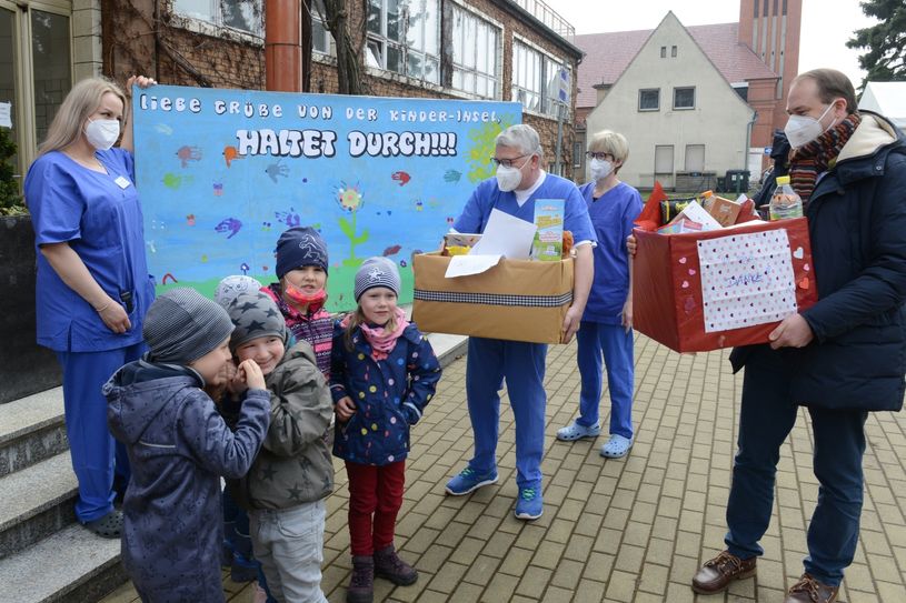 Tobias Vaasen, Geschäftsführer Klinikum Niederlausitz GmbH (re.), und Dr. Thomas Buthut, Leiter Impfstelle (Mitte), freuen sich über die Durchhaltepäckchen und das Frühlingsplakat der Kinder der Froggi-Kita aus Senftenberg. Foto:KNL/Steffen Rasche
