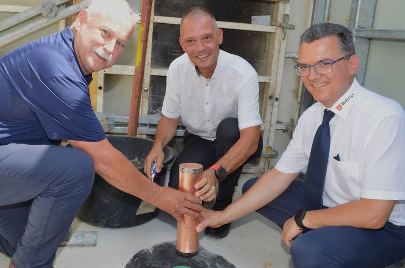 Großenhains Baubürgermeister Tilo Hönicke,  Landrat Ralf Hänsel und Rene Förster (v.l.), der für den Rettungsdienst Sachsen zuständige Geschäftsführer der Malteser, bringen die Zeitkapsel ins Fundament der neuen Rettungswache in Großenhain.