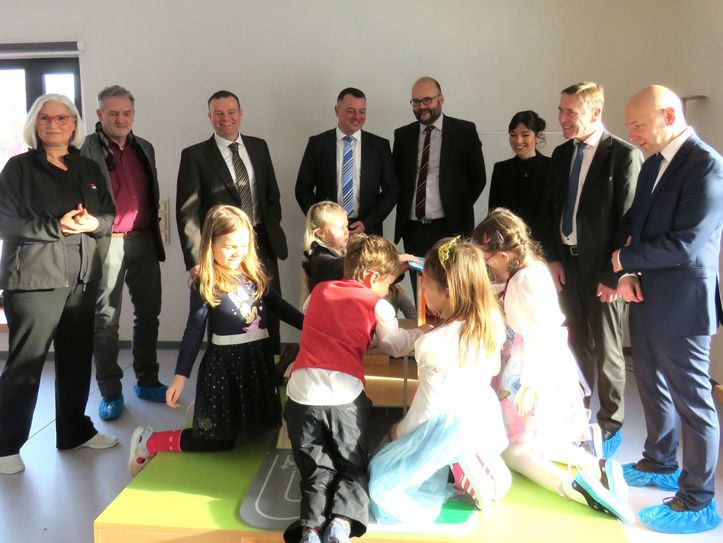 Die Kinder nahmen ihr neues Zuhause spielend in Besitz und ließen sich vom prominenten Besuch nicht stören: Marcus Beier, GF des AWO-KV Lausitz, CDU-Landtagsabgeordneter Aloysius Mikwauschk, Elaine Jentsch, Staatsminister Christian Piwarz, Landrat Udo Witschas, Bürgermeister Stefan Schneider, Landesgeschäftsführer der AWO Sachsen, David Eckardt, und die Leiterin der Einrichtung, Katrin Loewe (v.r.n.l.). Foto: Matthias Stark