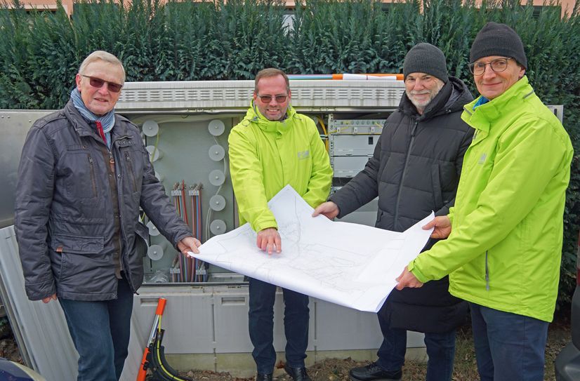 Ortsvorsteher Wolfgang Schneider (li). und Oberbürgermeister Uwe Rumberg (2.v.re.) lassen sich vor einem der bereits vorhandenen Glasfaserverteilerschränke von FSW-Geschäftsführer Matthias Leuschner (re.) und Jens Schulze, Geschäftsbereichsleiter Kundengeschäft bei der FSW GmbH, die Ausbaupläne für Pesterwitz zeigen.