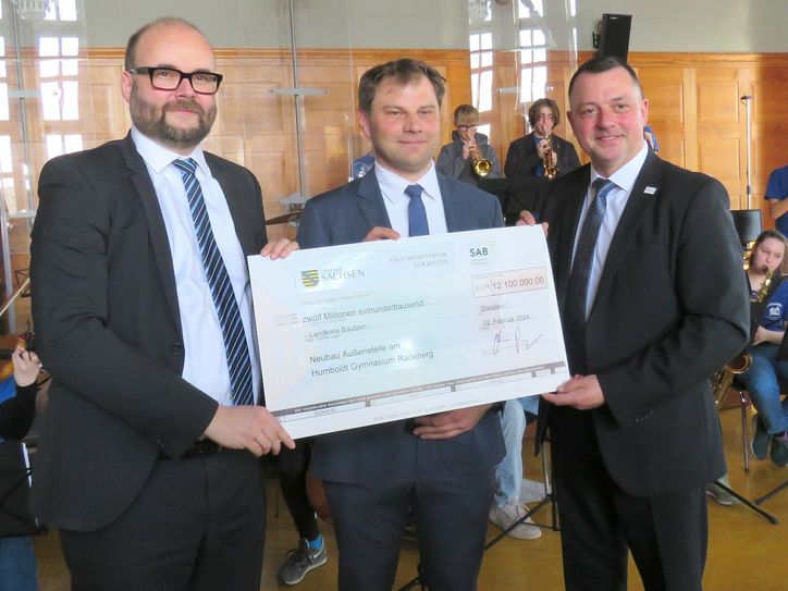 Kultusminister Christian Piwarz (l.) übergibt im Beisein von Schulleiter Andreas Känner (m.) den Fördermittelbescheid an den Landrat des Landkreises Bautzen, Udo Witschas (r.). Foto: Matthias Stark