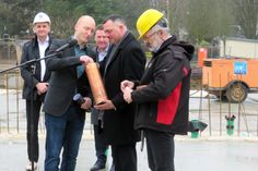 Schulleiter Maik Weinert (2.v.l.) befüllt gemeinsam mit Landrat Udo Witschas (2.v.r) die Zeitkapsel, die wenig später im Grundstein eingelassen wird. 
 Foto: Matthias Stark