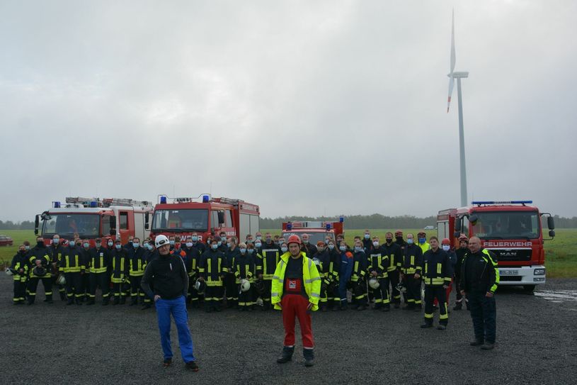 Gemeinsam haben Sie die Übung im Windpark Kittlitz II organisiert: Markus Romberg, technischer Geschäftsführer Repartner Wind GmbH (l.), Thomas Brossok, EMIS Windservice (Mitte) und Hartmut Wassermann, Stadtbrandmeister Lübbenau (r.), vor einem Teil der an der Ausbildung beteiligten Wehren bzw. deren Mitglieder. Foto: EMIS