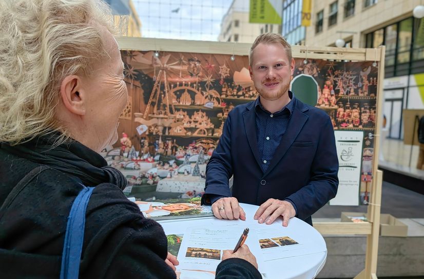 Frederic Günther vom Verband Erzgebirgischer Kunsthandwerker und Spielzeughersteller e.V. wirbt für die Handwerkskunst-Buden. Er hatte gerade Glück und findet eine Interessentin.