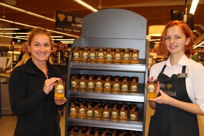 Juliane Scheller und Azubine Lisa Böhle, Bienenbeauftragte im Markt, präsentieren den ersten eigenen Honig, der auf dem Dach des Edeka-Einkaufsmarktes an der Hamburger Straße produziert wurde.