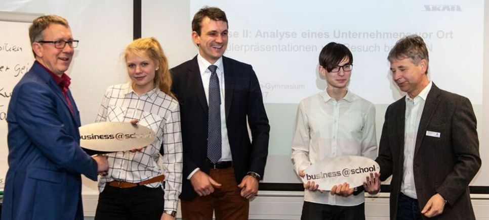 Die Schüler Pauline Donix und Enno Schubert erhalten aus den Händen von Hubertus Kaiser, Dr. Christoph Künne (Alumnus der Boston Consulting Group) und Mario Ludwig (SKAN AG) mit einen Hochleistungs-Laser aus Edelstahl ausgeschnittene business-at-school Logos als Siegerpreise. (von links). Bild (Doris Walkowiak)