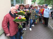 Die Schauspieler des Radeberger Biertheaters mischten sich unter die Wartendenden beim Kartenvorverkauf. Jene, die schon ganz zeitig da waren, erhielten einen Blumenstrauß aus den Hand des künstlerischen Leiters, Thomas Böttcher (m.).